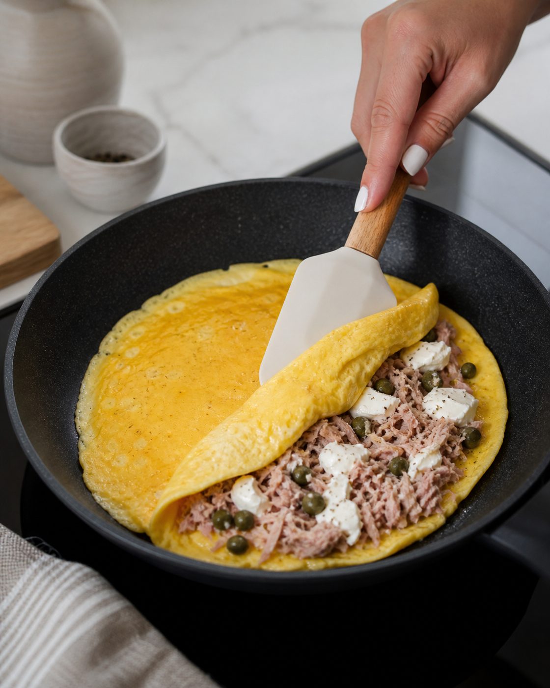 Schritt 2: Thunfisch, Kapern und Frischkäse auf eine Hälfte geben und das Omelett darüberklappen.