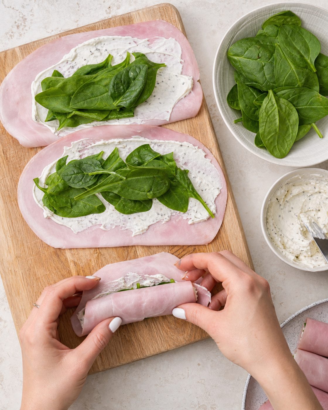 Schritt 1: Ich bestreiche die Schinkenscheiben dünn mit Frischkäse, lege Babyspinat darauf und rolle sie fest auf.