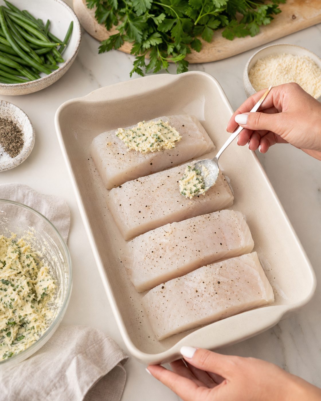 Schritt 1: Den gewürzten Kabeljau in die Form legen und die Masse aus Mandeln, Parmesan, Butter und Petersilie daraufstreichen.