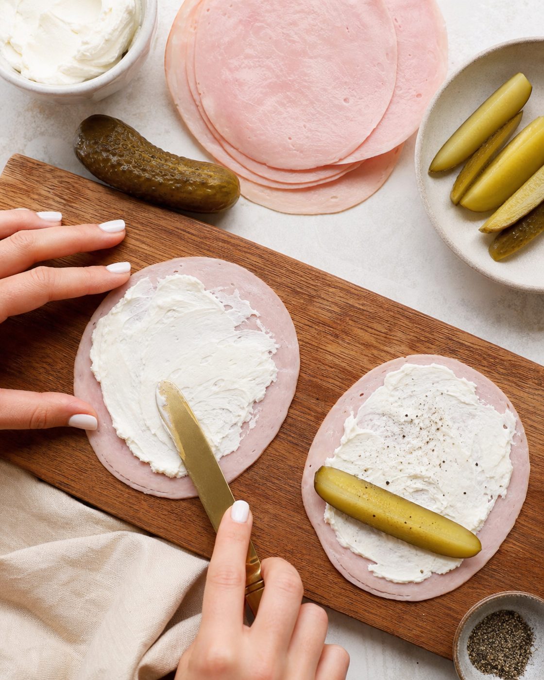 Schritt 1: Die Schinkenscheiben halbieren und gleichmäßig mit Frischkäse bestreichen.