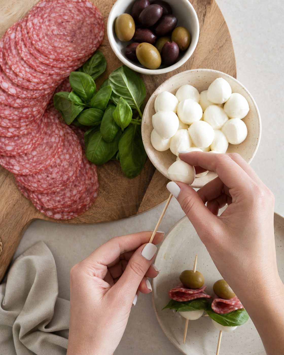 Schritt 1: Salami, Basilikum, Mozzarella und Olive der Reihe nach auf kleine Spieße stecken.