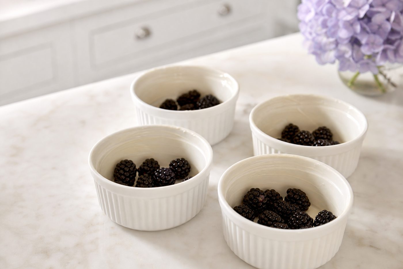 Schritt 1: Die Brombeeren gleichmäßig auf die vier gebutterten Förmchen verteilen.